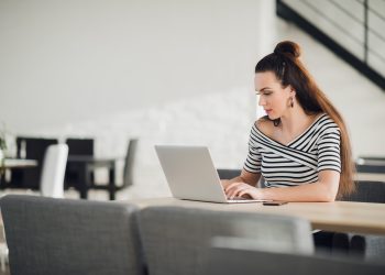 Attractive concentrated adult woman browsing the internet and searching information for business during lunchtime